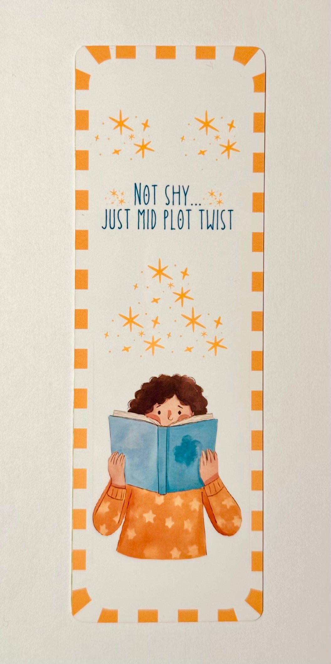 Bookmark with illustration of a person reading a book and text 'Not shy... just mid plot twist' on a light background.